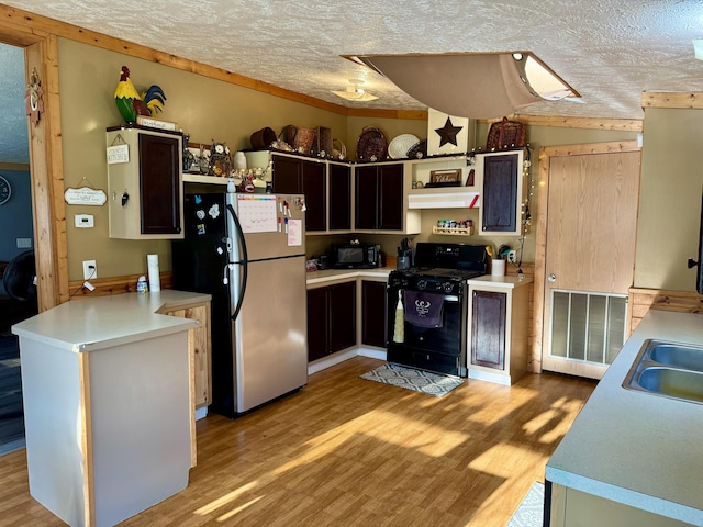 kitchen featuring light wood finished floors, a peninsula, a textured ceiling, and black appliances