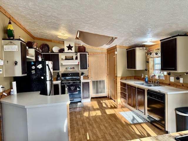 kitchen featuring light countertops, a sink, black appliances, a peninsula, and a textured ceiling