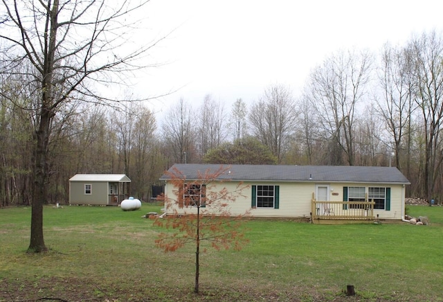 view of front of house with a shed, an outbuilding, a front yard, and a deck