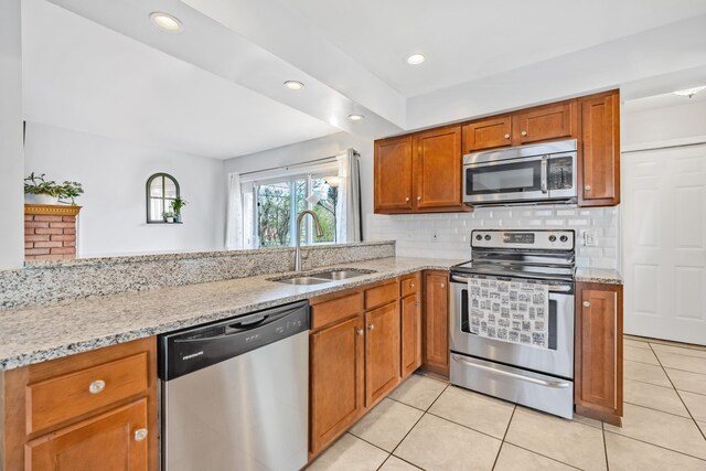 29772 Brentwood St, Southfield, MI 48076 - kitchen featuring light stone counters, a sink, brown cabinetry, light tile patterned floors, and stainless steel appliances