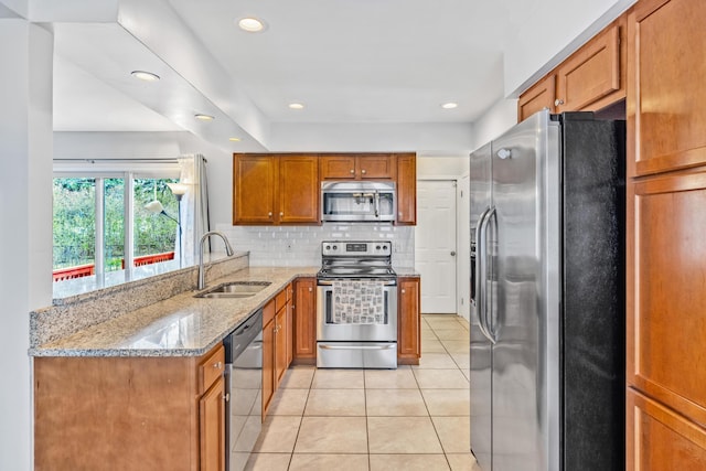 29772 Brentwood St, Southfield, MI 48076 - kitchen with a sink, brown cabinetry, light tile patterned floors, appliances with stainless steel finishes, and light stone countertops