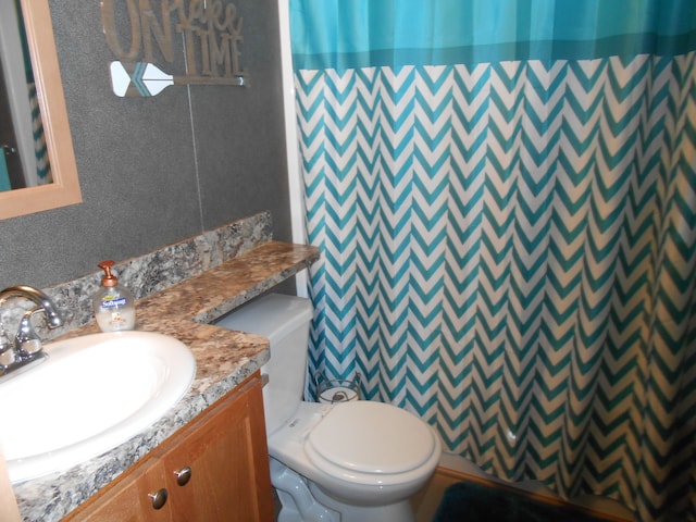 bathroom featuring a shower with curtain, vanity, and toilet