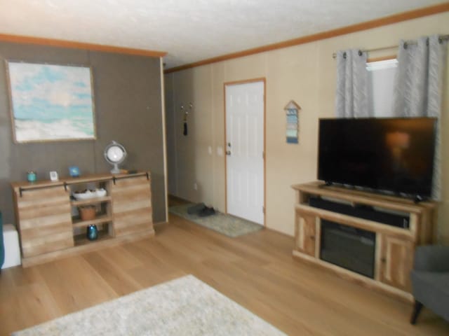 living area with wood finished floors and ornamental molding
