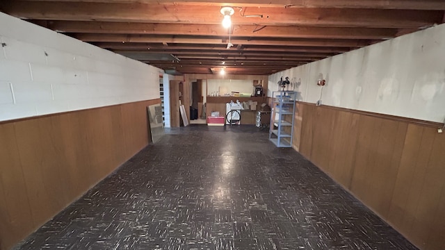 unfinished basement with tile patterned floors, wood walls, and wainscoting