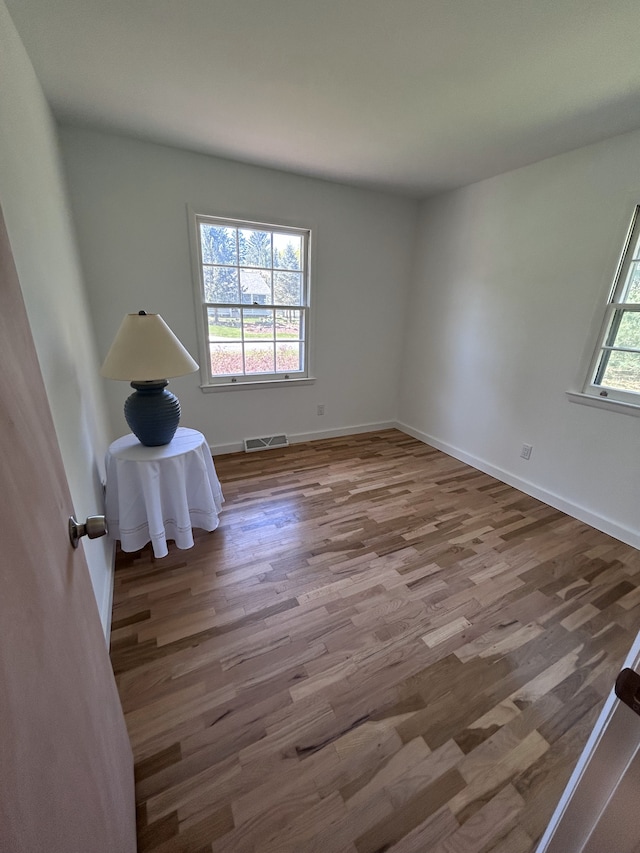 unfurnished room with visible vents, baseboards, and wood finished floors