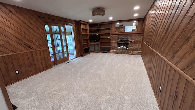 unfurnished living room with a fireplace, carpet floors, wood walls, recessed lighting, and visible vents