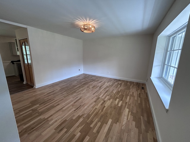 spare room featuring baseboards and wood finished floors