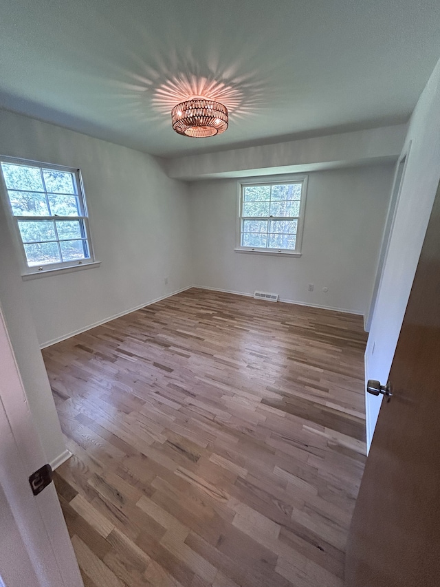 unfurnished bedroom with baseboards, wood finished floors, and visible vents