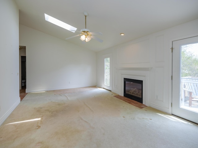 6273 S 12th St, Portage, MI 49024 - unfurnished living room with light colored carpet, a fireplace with flush hearth, plenty of natural light, and vaulted ceiling with skylight