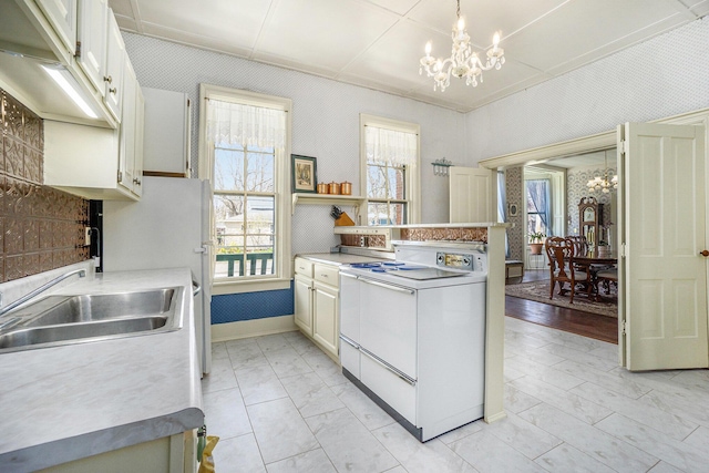 204 E Burr Oak St, Centreville, MI 49032 - kitchen with a wealth of natural light, a sink, a notable chandelier, and white appliances