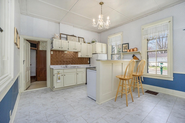 204 E Burr Oak St, Centreville, MI 49032 - kitchen with a sink, freestanding refrigerator, an inviting chandelier, wallpapered walls, and a breakfast bar