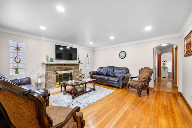 living area featuring recessed lighting, a fireplace, arched walkways, and light wood-style floors