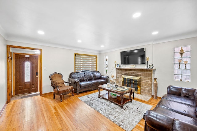 living room featuring plenty of natural light, baseboards, and a stone fireplace