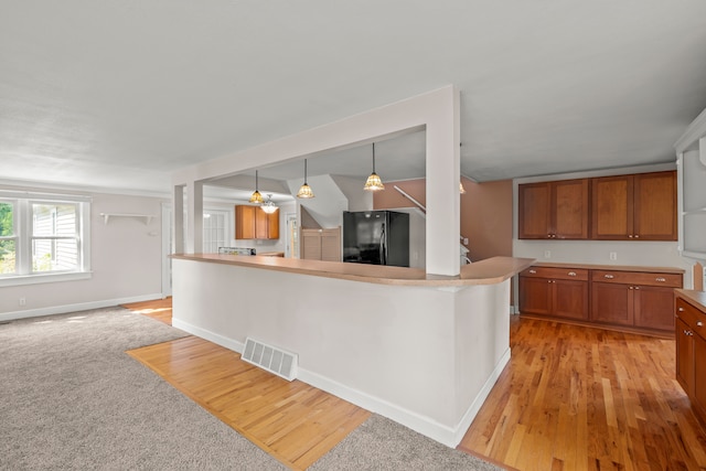 2316 Sugar Riv, Gladwin, MI 48624 - kitchen featuring light wood-style floors, freestanding refrigerator, brown cabinetry, and visible vents