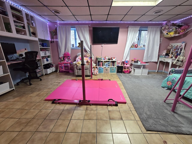 rec room with a drop ceiling, tile patterned flooring, and a desk