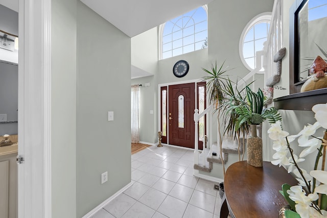 entrance foyer featuring baseboards, light tile patterned floors, and a towering ceiling