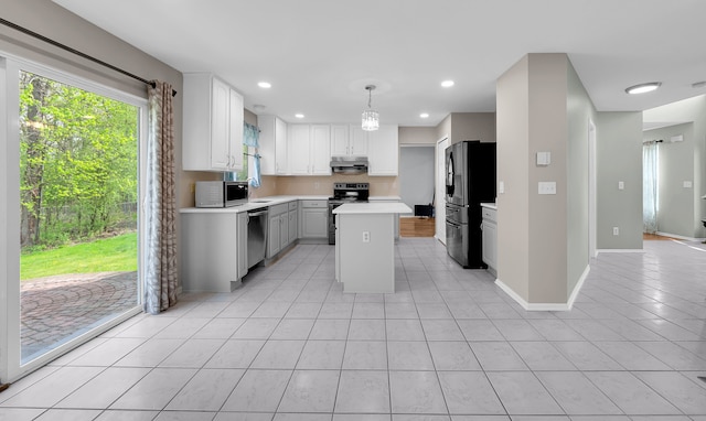 kitchen with light tile patterned flooring, a center island, light countertops, under cabinet range hood, and appliances with stainless steel finishes