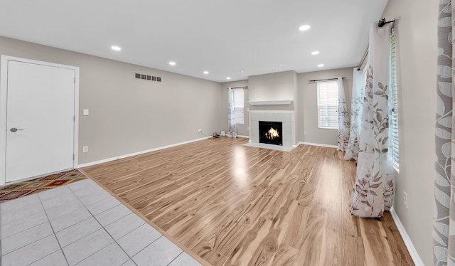 unfurnished living room featuring a fireplace with flush hearth, recessed lighting, light wood-style flooring, and visible vents