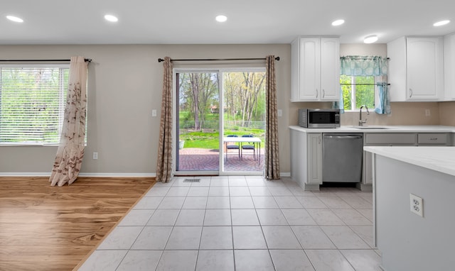 kitchen featuring light countertops, stainless steel appliances, white cabinetry, and a sink