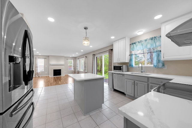 kitchen featuring open floor plan, extractor fan, a sink, appliances with stainless steel finishes, and light tile patterned floors