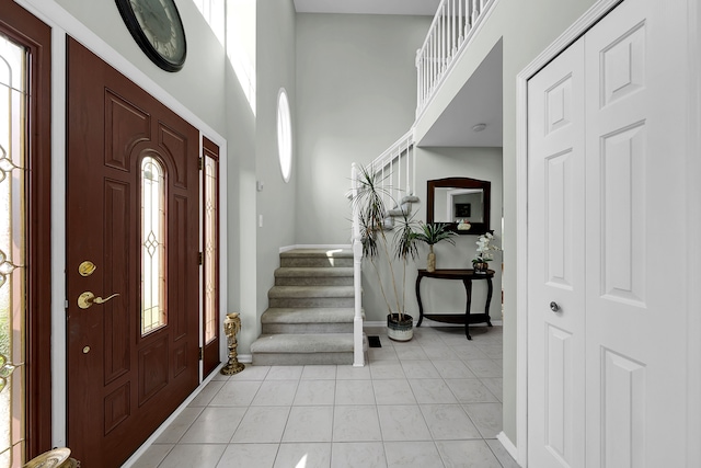 entrance foyer with light tile patterned flooring, baseboards, a high ceiling, and stairway