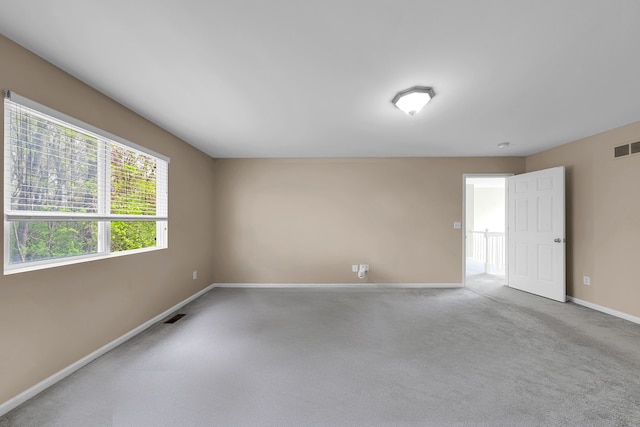 unfurnished room with baseboards, carpet, and visible vents