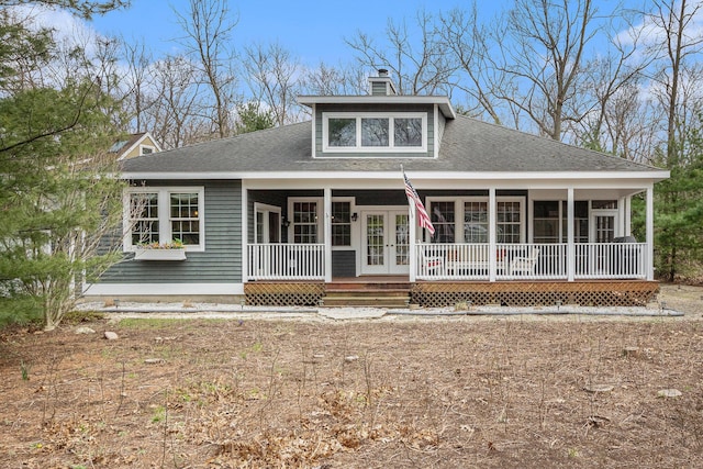rear view of property with a shingled roof, covered porch, a chimney, and french doors