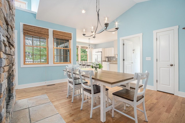 dining room with baseboards, light wood-style flooring, visible vents, and a notable chandelier