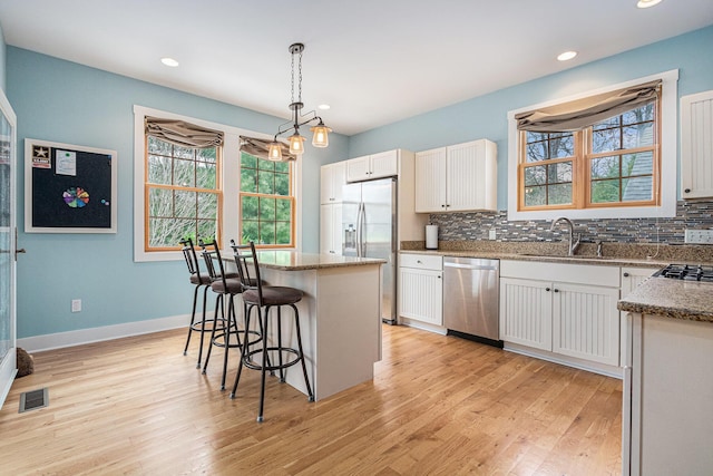 kitchen with stainless steel appliances, visible vents, a sink, and a wealth of natural light