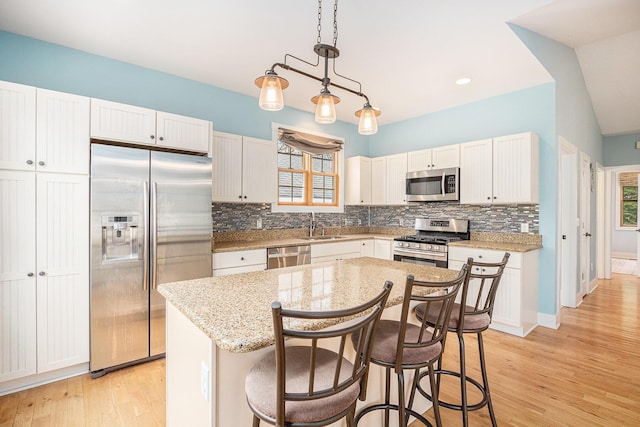 kitchen with backsplash, light wood-style floors, plenty of natural light, and appliances with stainless steel finishes