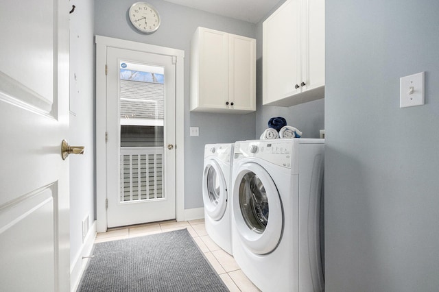 laundry area with washing machine and dryer, baseboards, light tile patterned flooring, and cabinet space