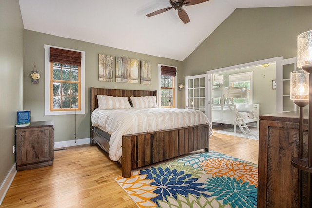 bedroom featuring high vaulted ceiling, baseboards, multiple windows, and light wood-style floors