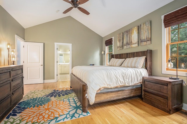 bedroom with light wood finished floors, vaulted ceiling, baseboards, ceiling fan, and ensuite bathroom