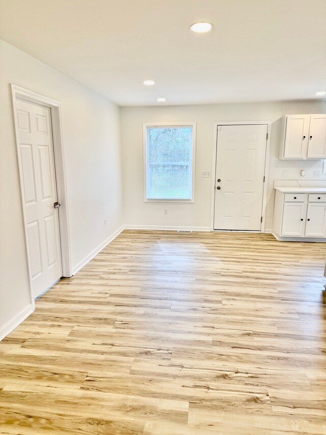 interior space with baseboards, recessed lighting, and light wood-type flooring