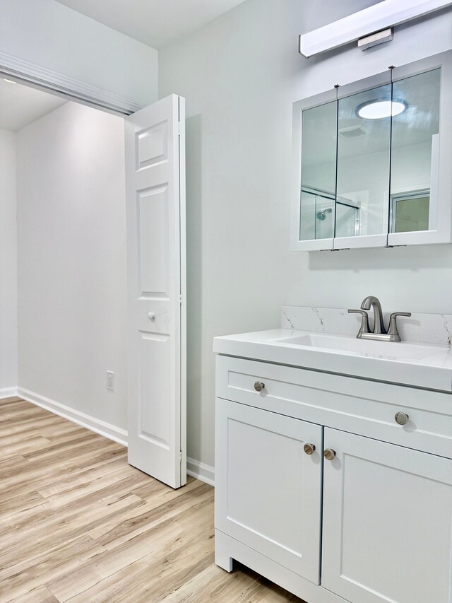 bathroom featuring baseboards, wood finished floors, and vanity
