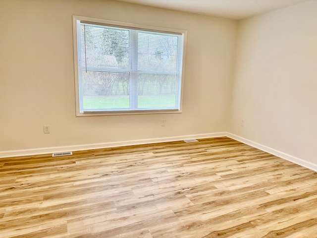 empty room featuring baseboards, wood finished floors, and visible vents