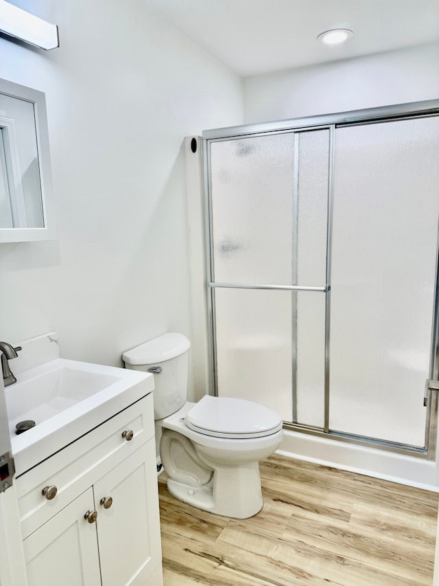 bathroom featuring vanity, wood finished floors, a shower stall, and toilet