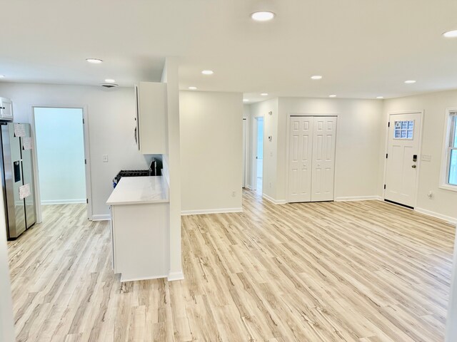 kitchen featuring stainless steel refrigerator with ice dispenser, light countertops, recessed lighting, and light wood-style floors