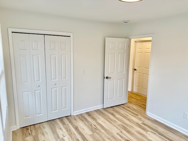 unfurnished bedroom with light wood-type flooring, baseboards, and a closet