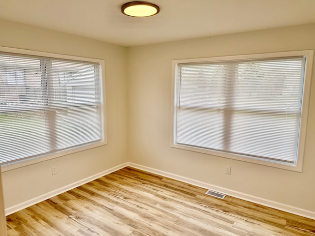 empty room with light wood-type flooring, baseboards, and visible vents