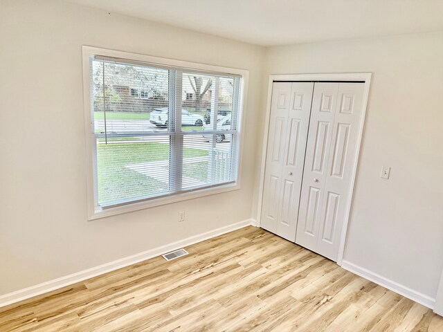 unfurnished bedroom with light wood-type flooring, baseboards, a closet, and visible vents