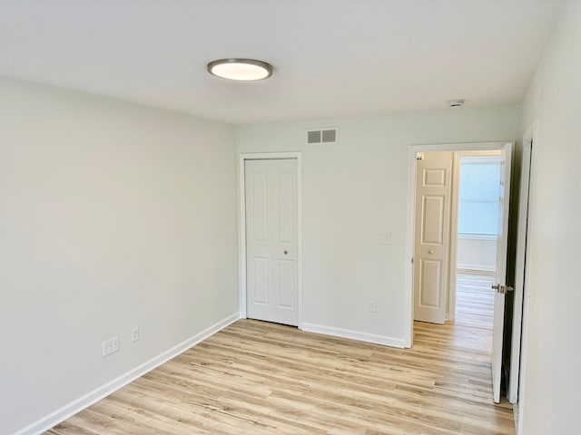 unfurnished room featuring visible vents, light wood finished floors, and baseboards