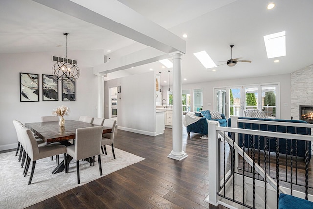 5591 Pioneer Ave, Saint Joseph, MI 49085 - dining space featuring dark wood-type flooring, vaulted ceiling with skylight, a stone fireplace, and visible vents
