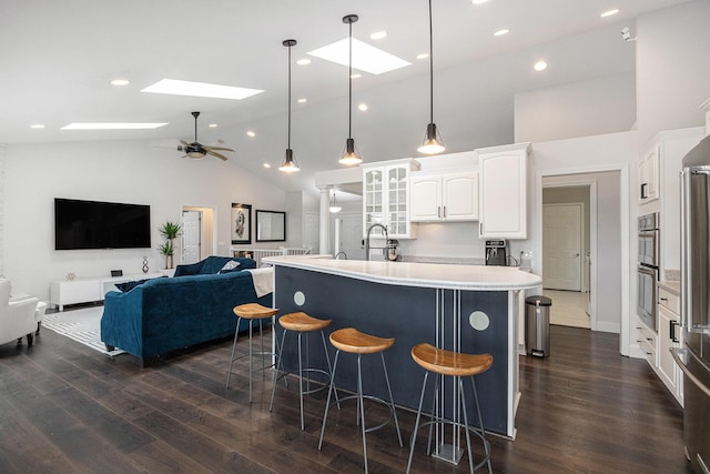 5591 Pioneer Ave, Saint Joseph, MI 49085 - kitchen with a kitchen bar, white cabinetry, a skylight, light countertops, and high vaulted ceiling