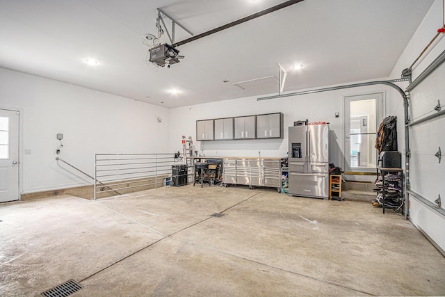 5591 Pioneer Ave, Saint Joseph, MI 49085 - garage with visible vents, stainless steel refrigerator with ice dispenser, and a garage door opener