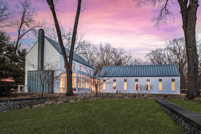 view of front of property featuring a garage, a front lawn, a chimney, and metal roof