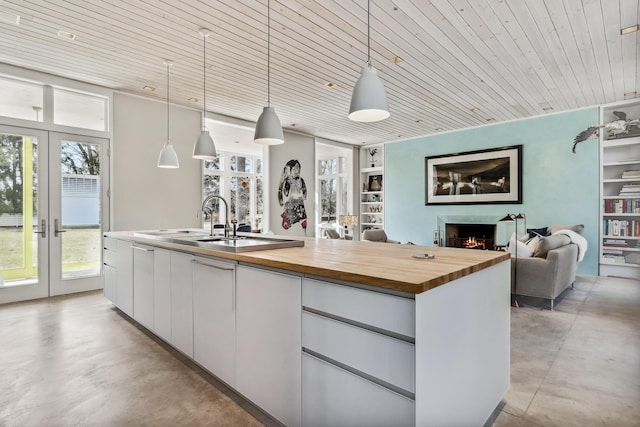 kitchen with french doors, white cabinets, concrete floors, open floor plan, and wood counters