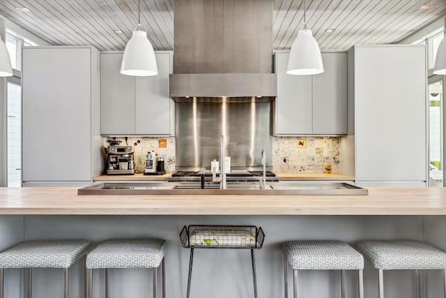 kitchen featuring wood counters, hanging light fixtures, and decorative backsplash