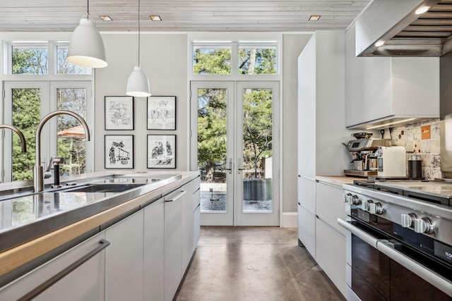 kitchen featuring wall chimney range hood, wood ceiling, french doors, range with two ovens, and white cabinets