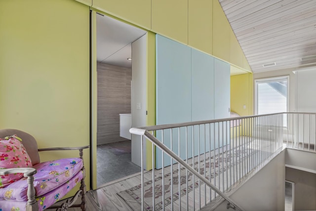 corridor with an upstairs landing and lofted ceiling
